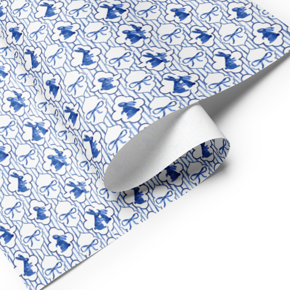 Blue and white patterned wrapping paper with a roll of paper on a white background
